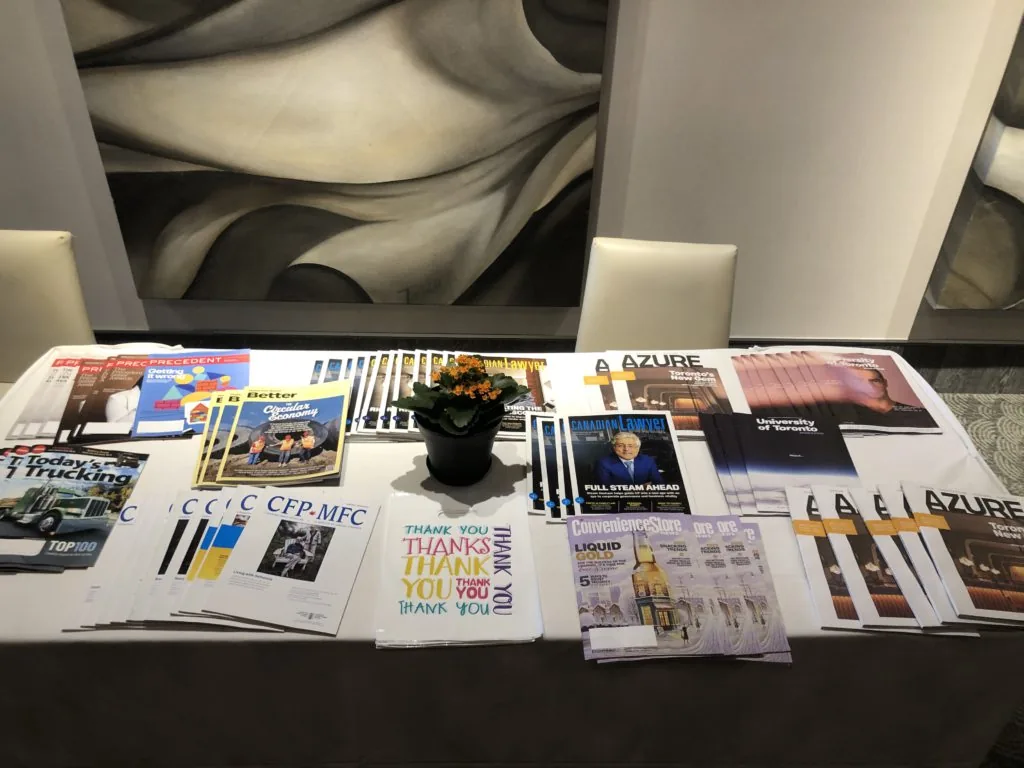 A table displaying magazine covers and hand-lettered Thank You cards spread around a potted plant